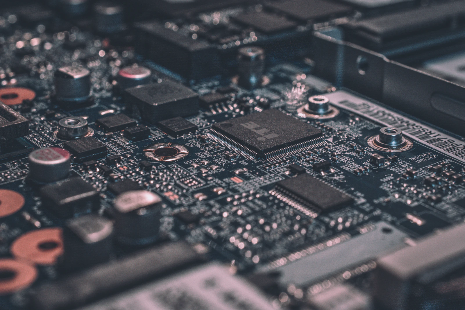 Detalhe macroscópico de uma placa de circuito impresso com tons azuis e magenta, simbolizando a engenharia de hardware e software